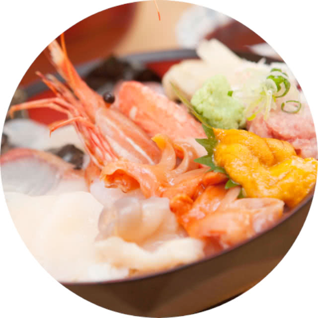 新鮮な海鮮丼。エビ、ウニ、刺身がたっぷり盛られ、わさびとネギが添えられている。